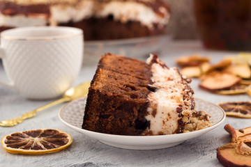 A portion of chocolate cake. A layer of white delicate meringue. Dried fruit slices. Light background.