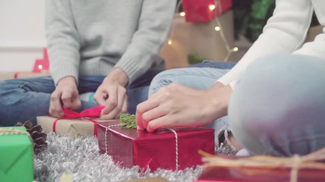 Lesbian Asian couple packing and wrapping Christmas present decorate her living room at home in Christmas Festival. Lifestyle lgbt women happy celebrate Christmas and New year concept.