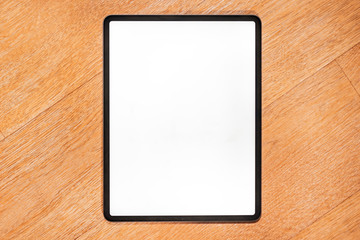 Isolated modern tablet computer on a wooden bench. Blank screen with bright lighting for design...