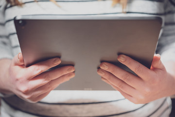 Woman using tablet computer with dramatic lighting and shallow depth of field. Blank screen with bright lighting for design mockups.
