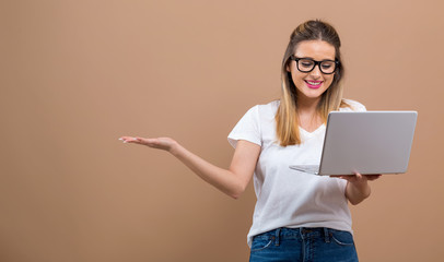 Young woman with a laptop computer on a brown background