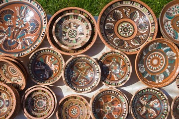 Fototapeta na wymiar many handmade and handpainted ceramic clay plates with floral and abstract pattern in the sunshine