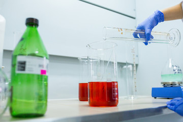 Hands of the scientist in the laboratory mixes with transfusion a chemical materials from graduated...