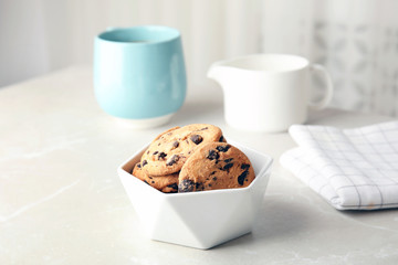 Bowl with tasty chocolate chip cookies on table