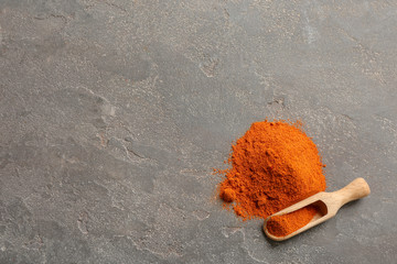 Wooden scoop and powdered pepper on gray background, top view with space for text