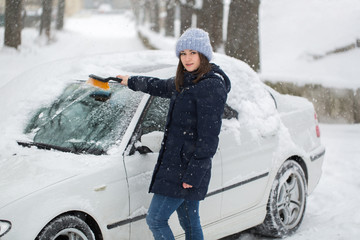 Woman removing snow from car windshield
