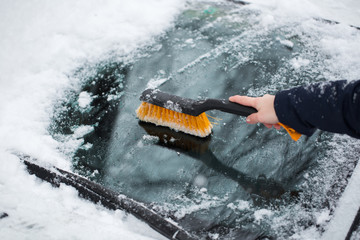 Woman removing snow from car windshield