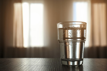 Glass of water on table against blurred background. Space for text