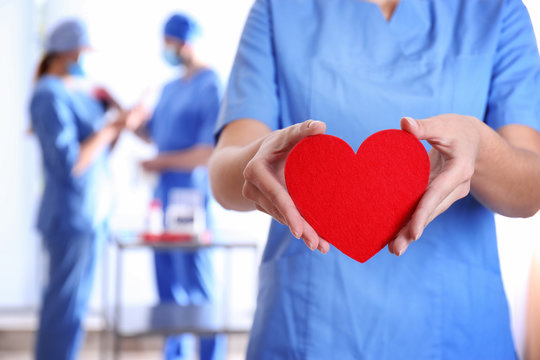 Doctor holding red heart at hospital, closeup. Donation day