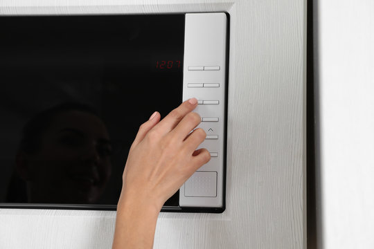 Young woman using microwave oven, closeup view