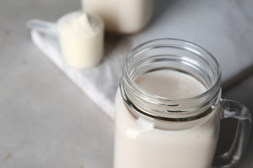 Mason jar with protein shake on table, closeup. Space for text