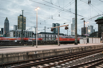 Naklejka premium Pociąg jedzie przez stację kolejową z dużym miastem w tle