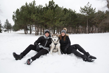 Fototapeta na wymiar Beautiful family, a man and a girl in winter forest with dog. Play with the dog Siberian husky.