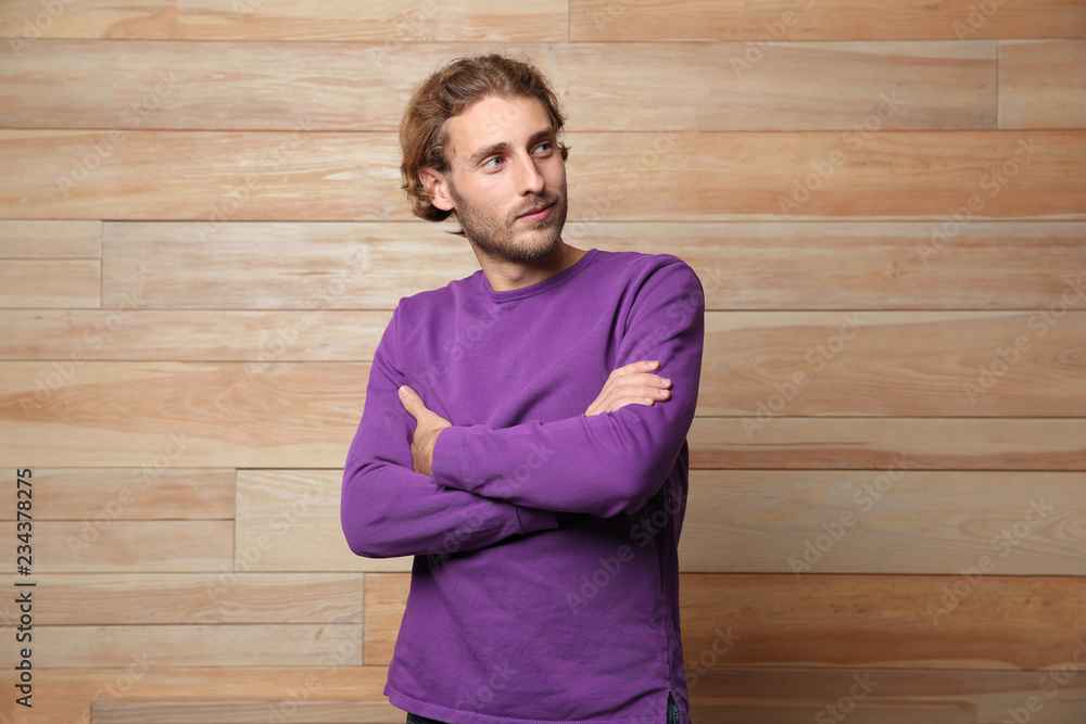 Sticker Handsome young man in warm sweater on wooden background