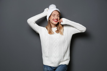 Beautiful young woman in warm sweater with hat on dark background