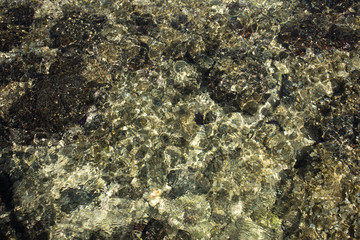 Abstract of the shallow water with light scatter from the pebbles in the crystal clear water. Makes an excellent computer screen background.