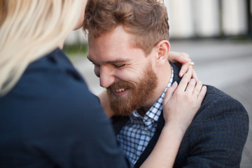 The man with the beard laughs, hugging his woman