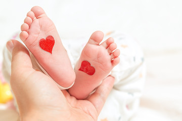 Father holds a small leg of a newborn baby. hearts for parents day or valentines day