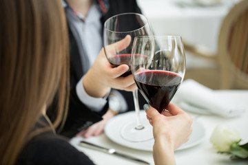 Beautiful young couple with glasses of red wine in luxury restaurant
