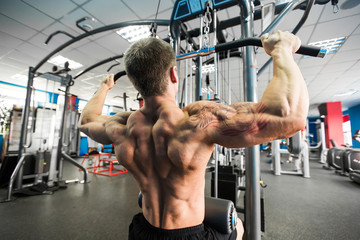 Shoulder pull down machine. Fitness man working out lat pulldown training at gym. Upper body...