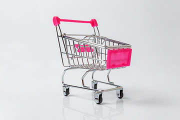 Small supermarket grocery push cart for shopping toy with wheels isolated on white background. Sale buy mall market shop consumer concept. Copy space