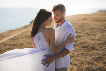 Beautiful young couple hugging in nature. People in white clothes.