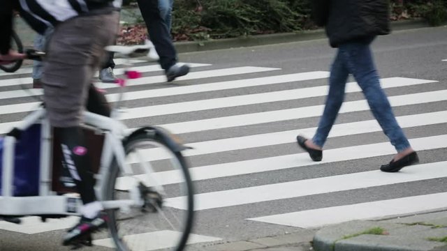 Pedestrians and cyclists crossing a busy street in a city.
