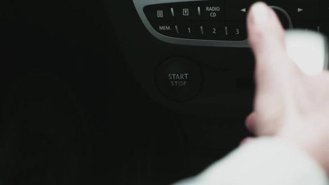 A woman starts a car with a start/stop button and changes gear with a gear shift lever.