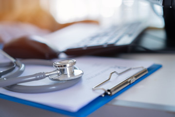 Medicine doctor's writing on laptop in medical office.Focus stethoscope on foreground table in hostpital.Stethoscope is acoustic medical device for auscultation,listening internal sounds of human body