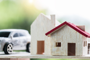 Property real estate investment concept : Wooden home, car on wooden blocks scale in balance on green background. Business investment and mortgage have to savings plans housing, loan money