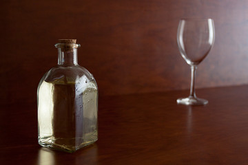 BOTELLA DE CRISTAL CON VINO BLANCO Y COPA AL FONDO 