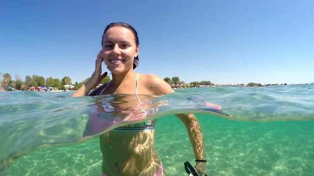 Beautiful fashion model girl relaxing during summer holiday in turquoise water smiling and giving kisses to camera, gopro dome shot