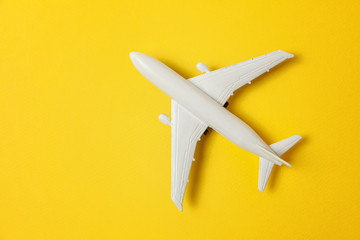 Simply flat lay design miniature toy model plane on yellow colorful paper trendy background. Travel by plane vacation summer weekend sea adventure trip journey ticket tour concept