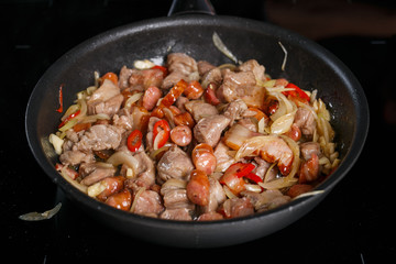 Frying pan with different kinds of meat, onions and chilli