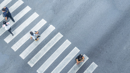 From the top view of people walk on street pedestrian crossroad in the city street with the motorcycle drives pass road ,bird eye view.