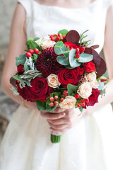 Wedding bouquet of flowers including Red hypericum, Roses, Lilies of the valley, mini Roses, Seeded Eucalyptus, Astilbe, Scabiosa, Pieris, and ivy