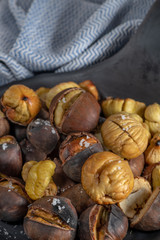 Roasted chestnuts in cast iron grilling pan over rustic wooden board.