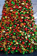 Red and green holiday ornaments on a Christmas tree