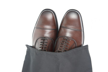 Classic men's brown Oxford shoes in protective black pouch on white background