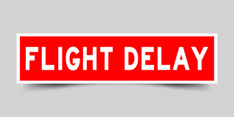 Square red sticker label in word flight delay on gray background