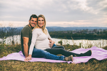 Husband and his pregnant wife enjoy spending time together outdoor.