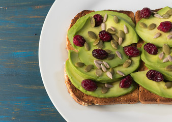 Vegetarian avocado toast with red cranberries and pipes