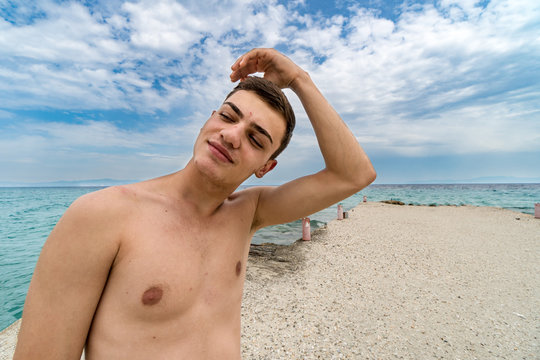 Portrait of surfer making his hairstyle. Young man taking selfie on the sea beach