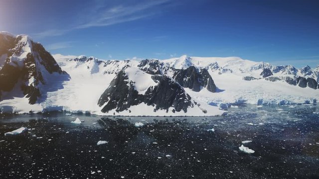 Aerial Flight Over Snow Mountains. Antarctica Shoreline. Drone View Of Snow, Ice Covered South Pole Surface, Cold Ocean. Amazing Winter Background. Lemaire Channel. 4k Footage.