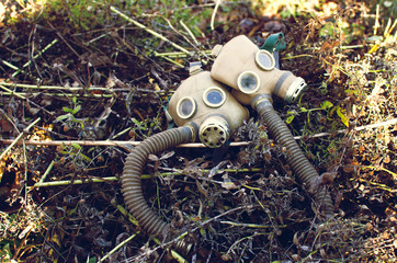 two gas masks lying among the dead withered grass