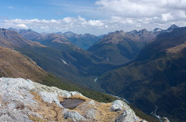 A lake, a river and mountains as seen from the top of the Conical Hill at the Harris Saddle at the Routeburn Great Walk, New Zealand