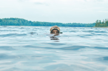 man in a mask for snorkeling swims with his head above the water surface