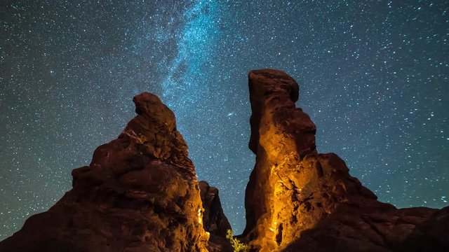 Starry sky time lapse over illuminated red rock landscape in Arches National Park