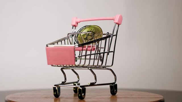 Shopping cart or market basket with cryptocurrency bitcoins on white background. Concept of online store