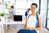 Portrait of smiling afro-american office worker in offfice with her colleagues